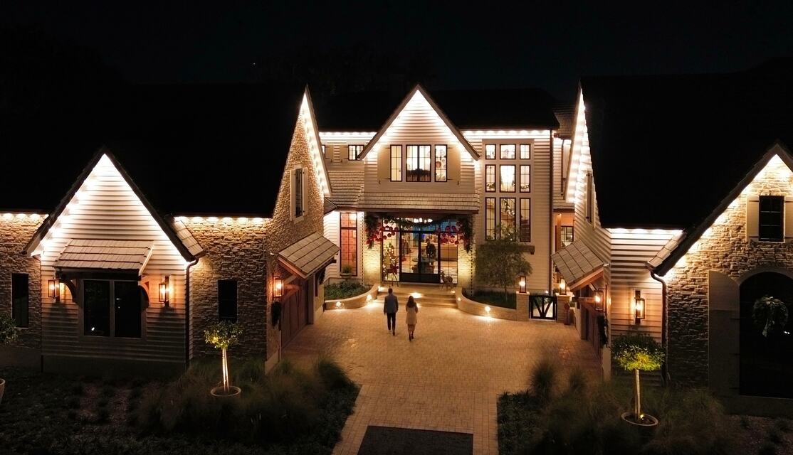 Large home with warm white rooflines and a lit front walkway