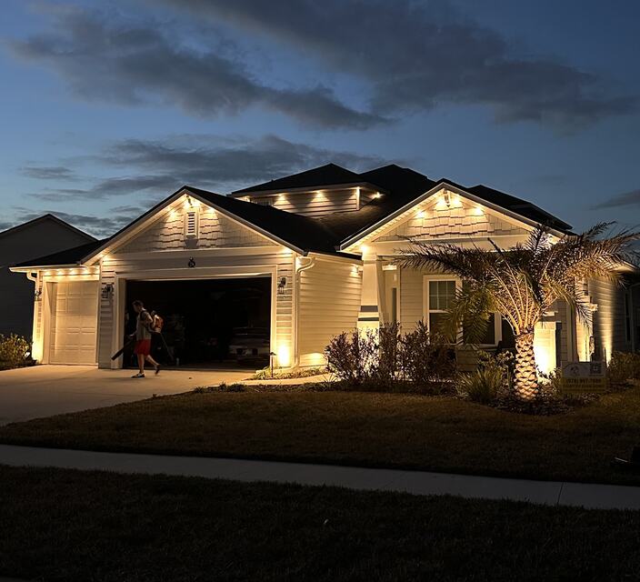 Home with warm white roofline lights and an uplit palm tree