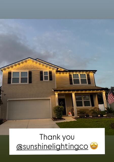 A customer's two-story home with warm white roofline lights and a thank-you note